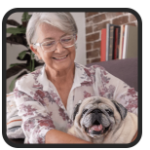 Smiling senior woman wearing glasses cuddling her pug on a living-room sofa